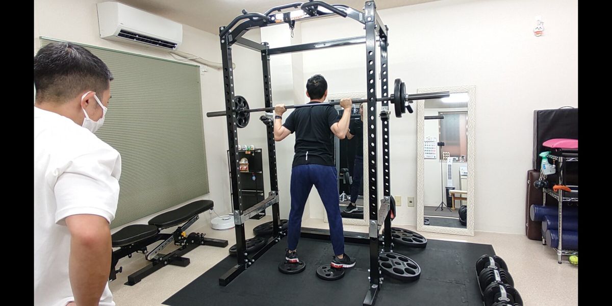 トレーナーの指導を受けながら背中を鍛えるお客様