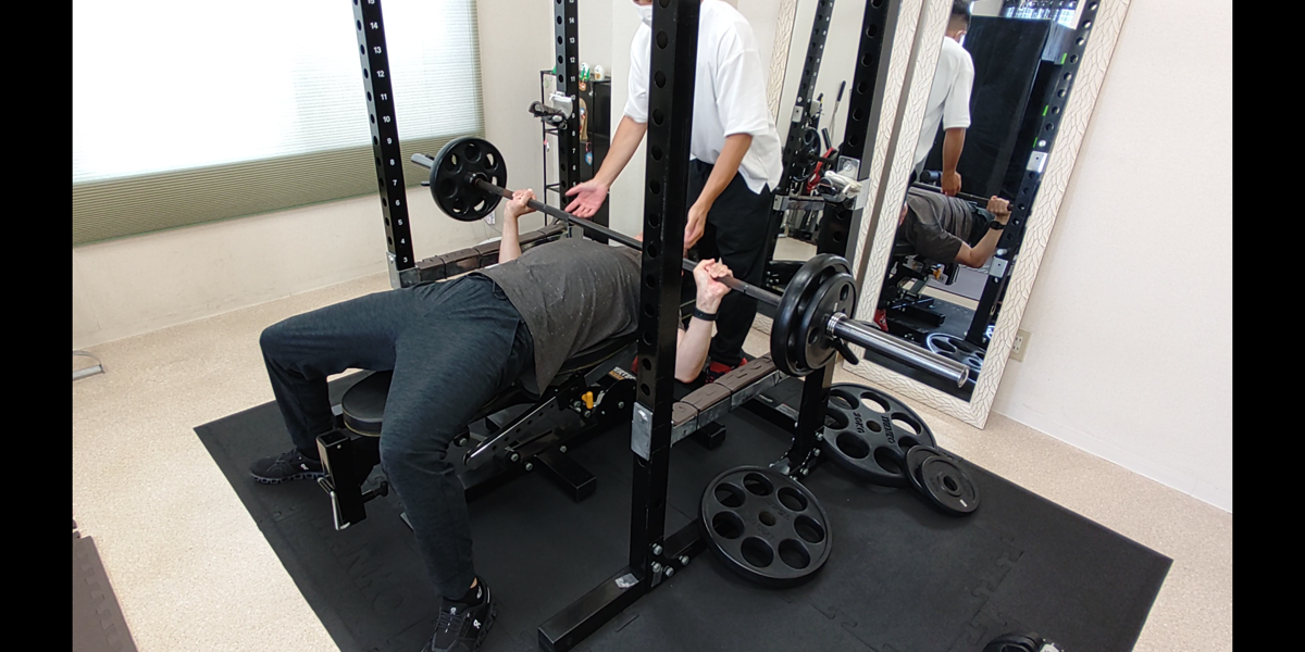トレーナーが見守る中でベンチプレスを行うお客様