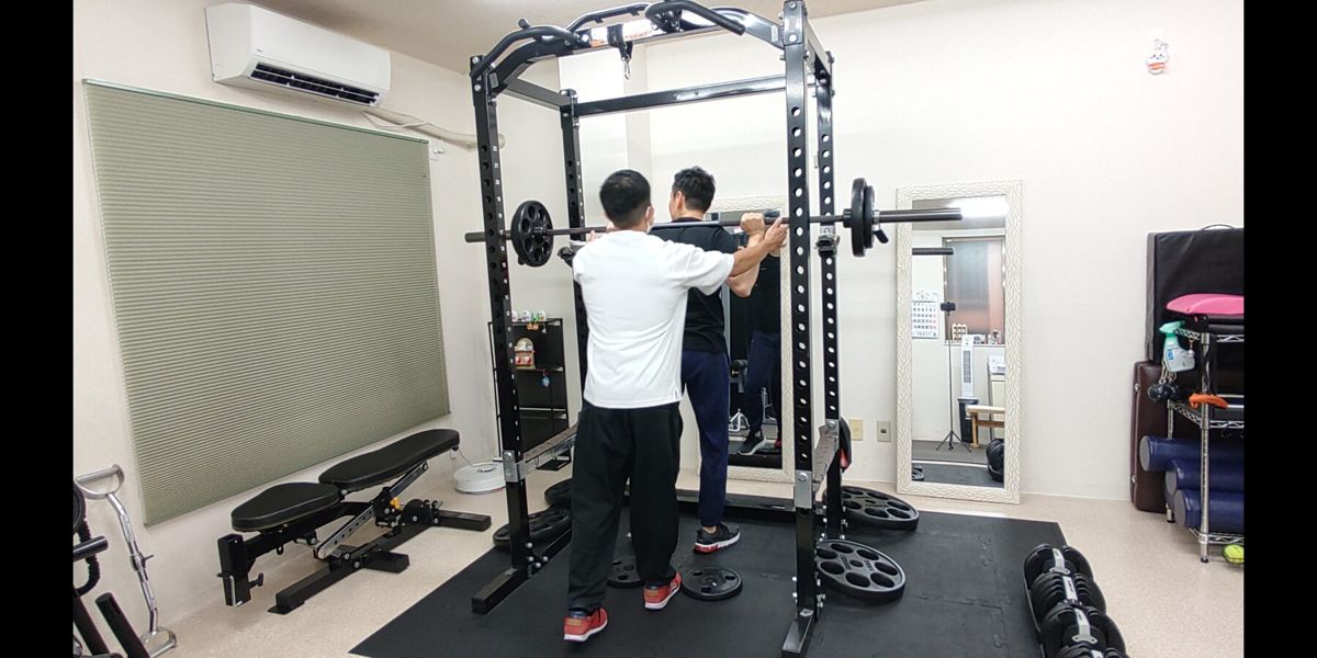 トレーナーが後ろから運動フォームを確認する様子