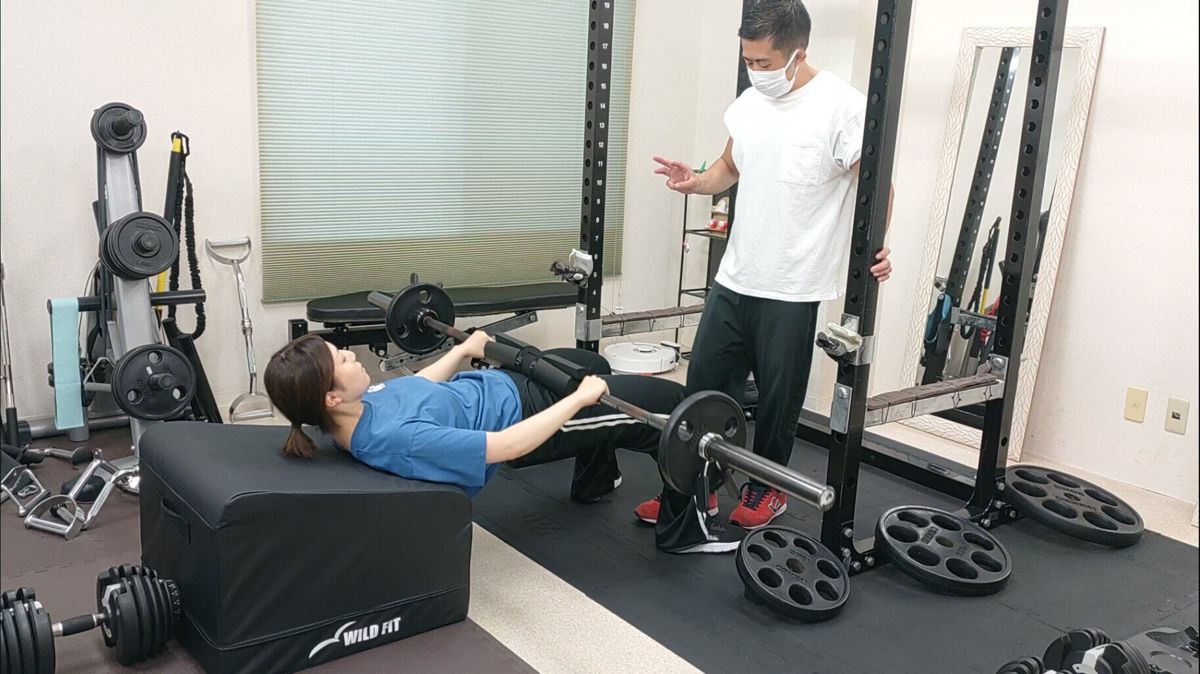 トレーナーの指導を受けながらヒップスラストを行うお客様