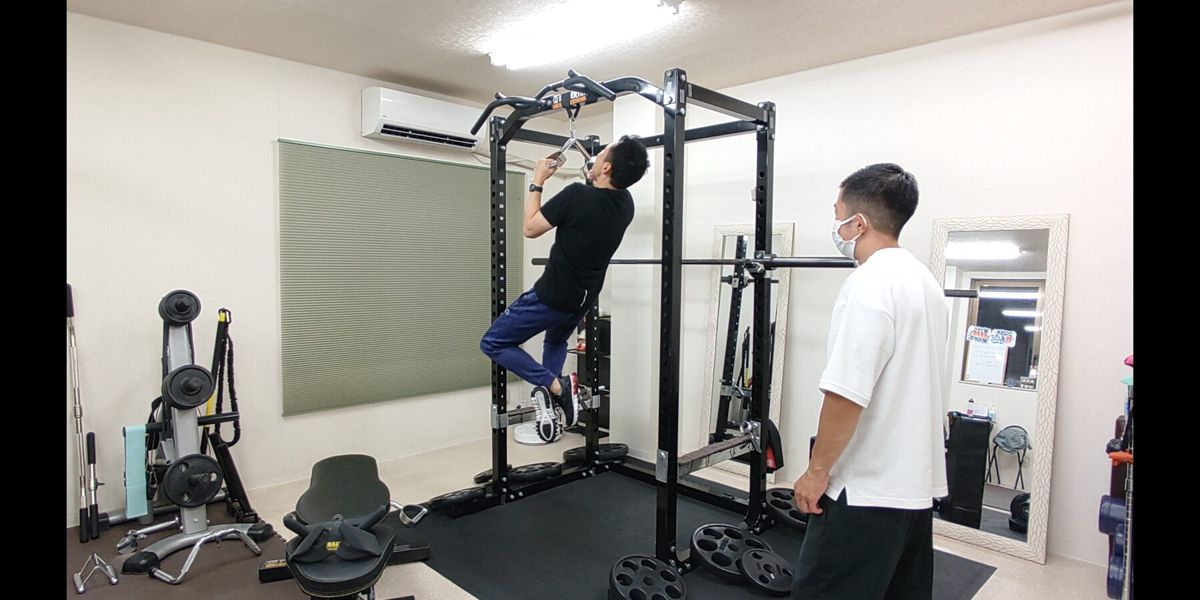 トレーナーのサポートを受けながら懸垂を行うお客様