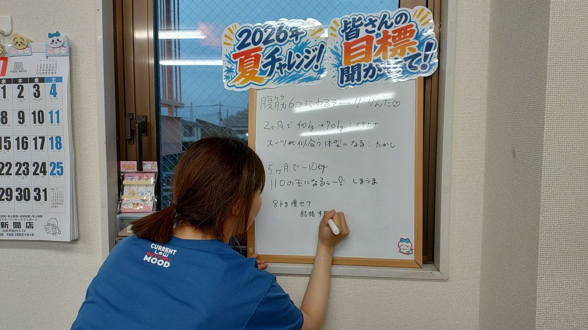 お客様がホワイトボードに2026年夏の目標を書き込む様子