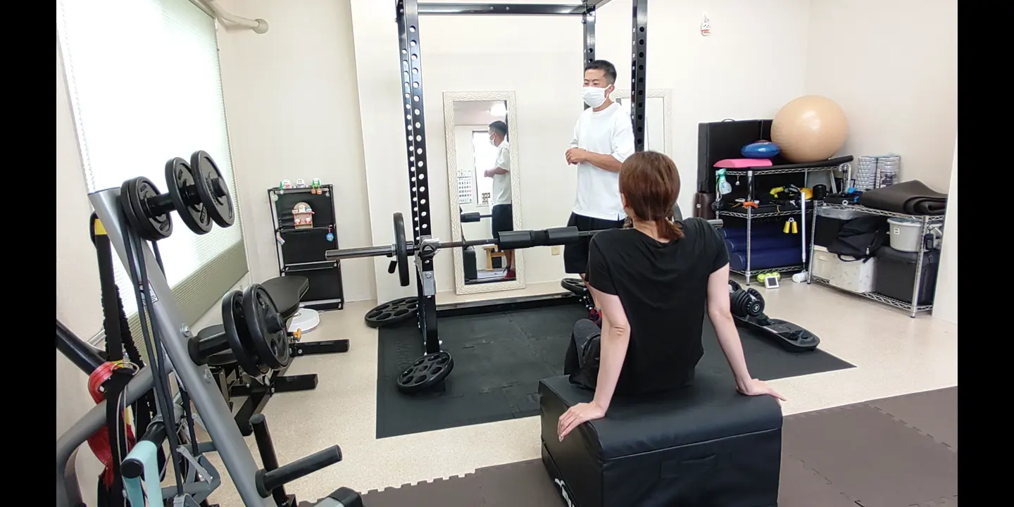 ベンチに座ったお客様へトレーナーがフォームを説明する様子