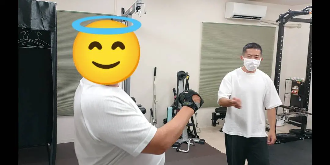 ダンベルカールを行うお客様へトレーナーが動きを説明する様子