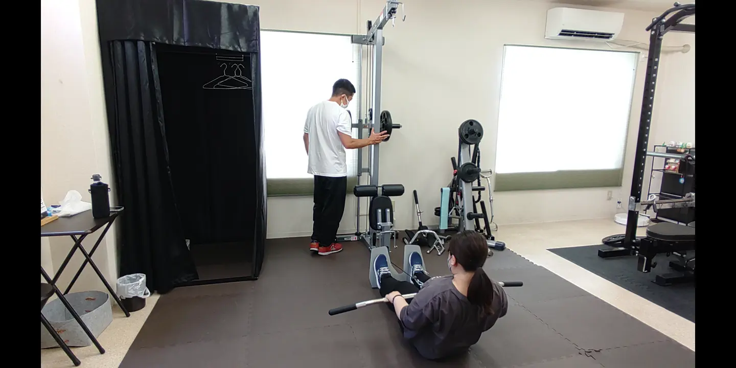 トレーナーがシーテッドローを行うお客様をサポートする様子