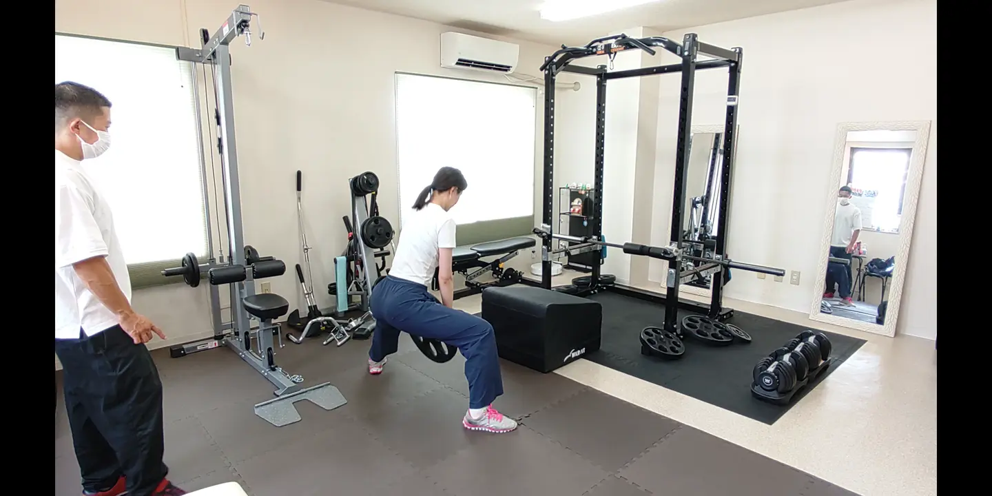 トレーナーの指導を受けながらスプリットスクワットを行うお客様
